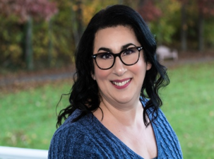 A woman with glasses is smiling for the camera.