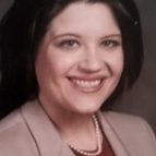 A woman with dark hair and a pink jacket.